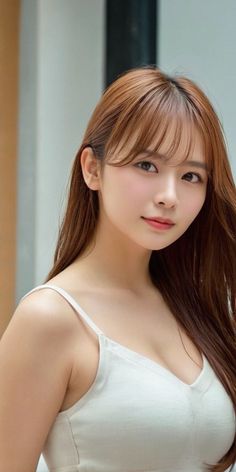 Woman with long brown hair wearing a white camisole, looking at the camera