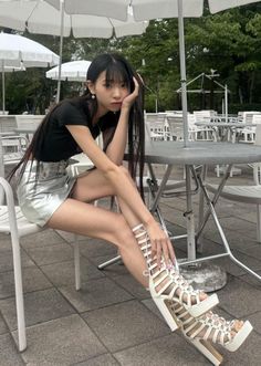 Woman with long black hair and a silver skirt sitting outdoors