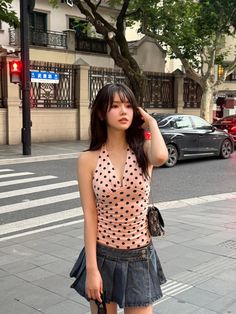 Woman in a polka dot top and denim skirt on a city street