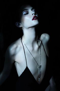 Woman with red lipstick and a long necklace in dramatic lighting