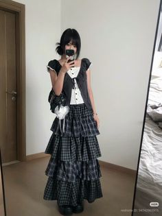 Person in a plaid tiered skirt and ruffle top taking a mirror selfie