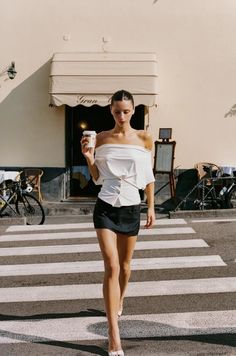 Woman in an off-shoulder top and mini skirt walking on a pedestrian crossing