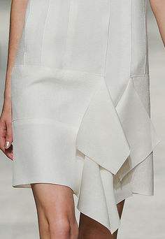 Close up of a white dress with a ruffled skirt and textured fabric