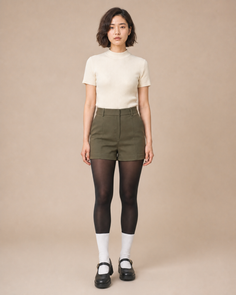 Woman with short hair wearing a ribbed top, olive shorts, and black tights