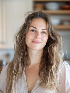 Woman with long wavy light brown hair smiling in an indoor setting