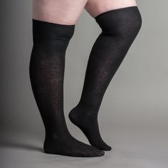 Person wearing black thigh-high socks against a gray background