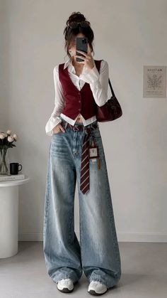 Woman in a red vest and wide leg jeans taking a mirror selfie