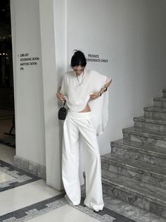 Woman in a white outfit with a cropped top and wide leg pants indoors