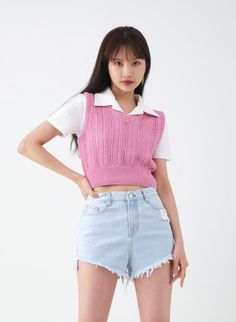 Woman in a pink knit vest and denim shorts posing in a studio