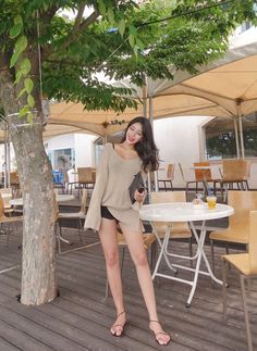 Woman in an oversized sweater and shorts at an outdoor cafe