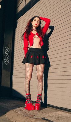 Woman in a red top, mini skirt, and fishnet stockings posing outdoors