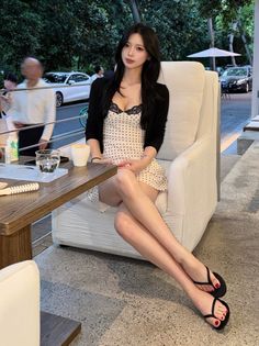Woman in a polka dot dress and black cardigan sitting at an outdoor cafe