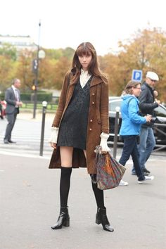 Woman in a brown coat and black dress with knee-high socks on a street
