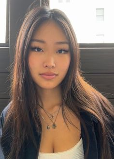 Woman with long dark hair and layered necklaces, showing cleavage