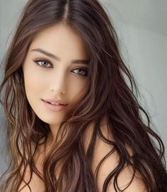 Woman with long wavy brown hair and hazel eyes, looking at the camera