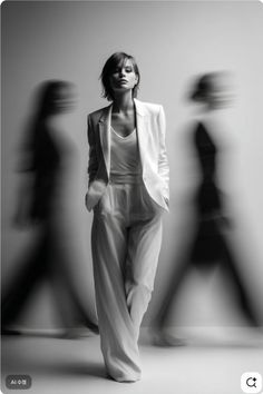 Woman in a white suit with blurred figures in a monochrome studio shot