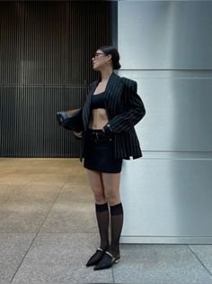 Woman in a pinstripe blazer, crop top, and mini skirt outdoors
