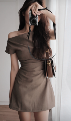 Woman in an off-shoulder dress taking a mirror selfie with a camera