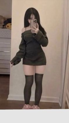 Woman in an off-shoulder top and thigh-high socks taking a mirror selfie