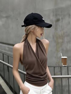 Woman with blonde hair and a baseball cap wearing a brown halter top