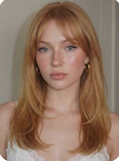 Woman with red hair and freckles wearing hoop earrings and a white lace top