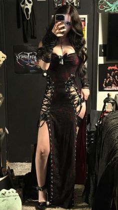 Woman in a gothic dress with lace-up sides and long dark hair taking a mirror selfie