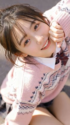 Young woman in a pink sweater and school uniform smiling outdoors