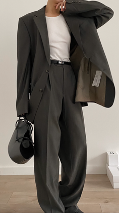 Person in a dark suit and white tank top holding a black handbag
