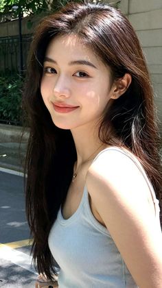 Woman with long dark hair wearing a tank top and necklace outdoors