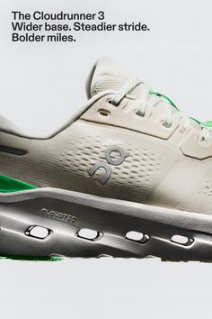 Close up of a white running shoe with green accents on a white background