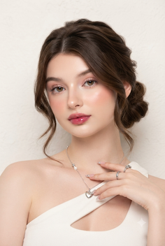 Woman with brown hair in an updo wearing a white top and jewelry