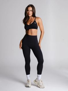 Woman in a black sports bra and leggings posing in a studio