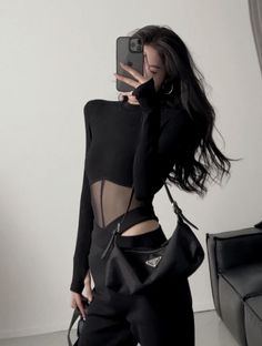 Woman in a black top with sheer panels taking a mirror selfie