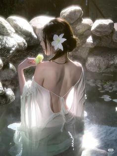 Woman in a white dress with an exposed back in water with soft lighting