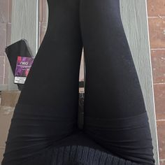 Person wearing black leggings with a phone and cigarette pack nearby