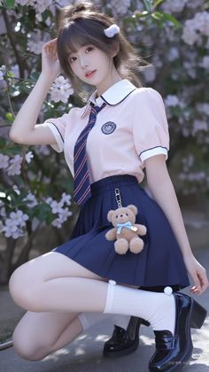 Girl in a school uniform with a teddy bear charm, crouching outdoors