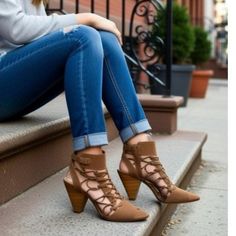 Person in blue jeans and brown lace-up heels sitting on outdoor steps