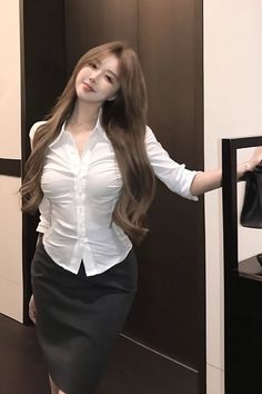 Woman with long brown hair wearing a white shirt and pencil skirt indoors
