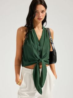 Woman in a green tied top and white pants with a black handbag