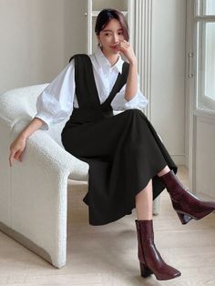 Woman in a black dress and white shirt sitting on a chair indoors