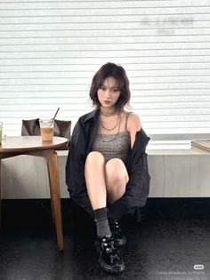 Woman with short hair wearing a leopard print top and black shirt, sitting indoors