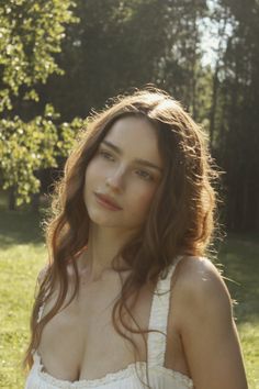 Woman with long wavy hair in a white dress outdoors with soft backlight