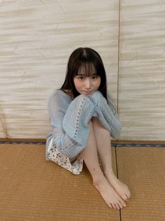 Woman with long dark hair and bangs sitting on a tatami mat