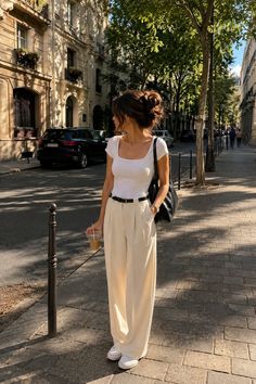 Woman with a messy bun wearing a white t-shirt and wide leg pants on a city street