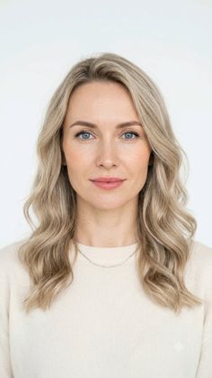 Woman with blonde wavy hair and blue eyes wearing a light sweater