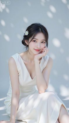 Woman in a white dress with a flower in her hair, sitting with soft lighting