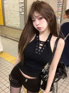 Woman in a black top and shorts posing in a subway station