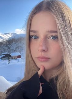Young woman with blonde hair and blue eyes in a snowy mountain landscape