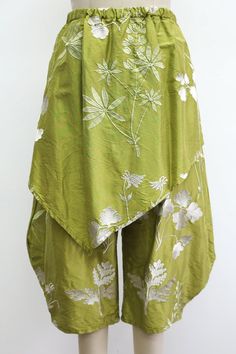 Green wide-leg pants with white floral embroidery and an asymmetrical overlay