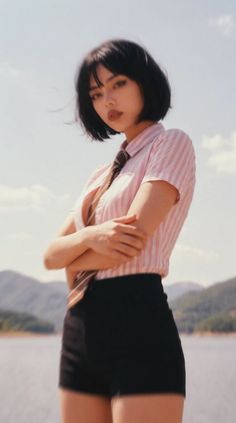 Woman with short black hair wearing a striped shirt and tie outdoors by a lake